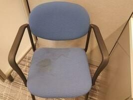 blue office chair with stains on grey carpet in cubicle photo