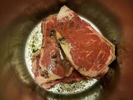 beef steak with seasoning and liquid in metal pot photo