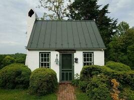 brick path or trail with green bushes and house or shed with bell and trees photo