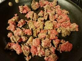 raw and cooked beef in frying pan with oil photo