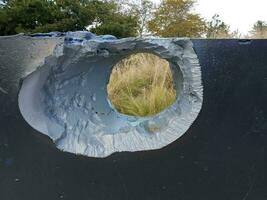 hole or damage in metal wall with trees photo