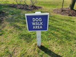 blue dog walk area sign on grass or lawn photo