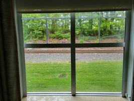 hotel window with railroad track and green grass photo