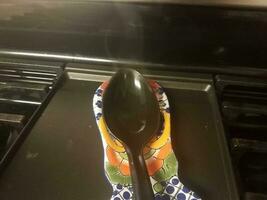 black spoon with steam on stove top photo