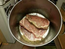 hand holding steak in metal pot in kitchen with seasoning photo