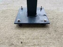 black metal post with screws on grey cement photo