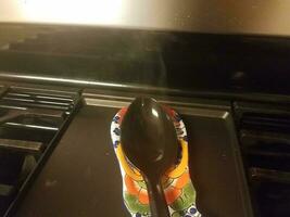 black spoon with steam on stove top photo