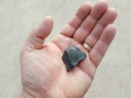 hand holding black burnt piece of wood over cement photo