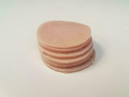 stack of circular pink ham meat on white surface photo