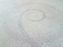 black spiral skidmark on black asphalt or pavement photo