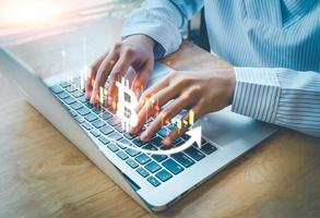 Cryptocurrency Investment with blockchain technology, bitcoin on candle graph, trade uptrend, save and make a profit with interest, Finance And Investment Concept, woman is typing laptop. photo