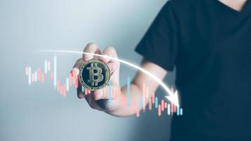 Cryptocurrency Investor holding bitcoin concept, businessman forecast and analysis graph with Bearish downtrend, Blockchain technology, effect of high inflation to investment, Decentralized finance. photo