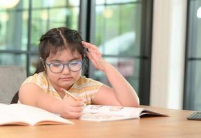 las chicas asiáticas están estudiando en tutoría, estudiando en línea en casa, las chicas están aburridas y cansadas de la tutoría. foto