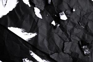 Black paper with white tears for the background. Crumpled paper texture with messy tears. photo
