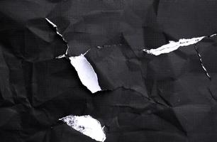 Black paper with white tears for the background. Crumpled paper texture with messy tears. photo