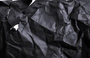 Black paper with white tears for the background. Crumpled paper texture with messy tears. photo