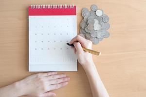 Hand writing in calendar plan and coins concept photo