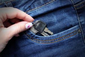 Woman hand takes out two keys from a jeans pocket photo