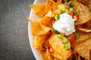 nachos tortilla chips with jalapeno, guacamole, tomatoes salsa and dip photo