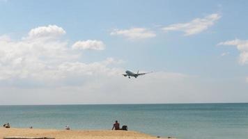 mensen op het mai khao-strand kijken naar het vliegtuig dat op de luchthaven van phuket landt. video