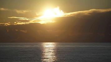 8k geweldige zonsondergangkleuren van achter de wolken boven de zee video