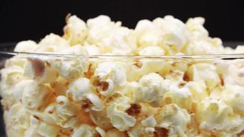 Gießen Sie Popcorn in ein rotierendes Glas auf schwarzem Hintergrund. video