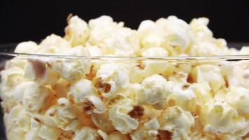 giet popcorn in een roterend glas op een zwarte achtergrond. video