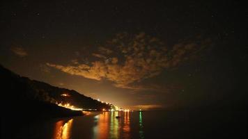 8k estrellas en el cielo nocturno y luces del puerto junto al mar video