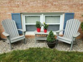 windows and blue shutters and chairs and plants and rocks photo