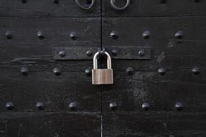 Metal padlock at an old wooden gate with metal bolts photo