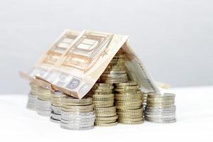 una casa hecha con monedas y billetes de euro - hipoteca, alquiler, inversión foto