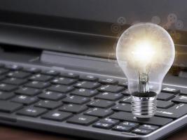 Laptop and glowing light bulb. Self learning or education knowledge and business studying concept. Idea of learning online or e-learning from home photo