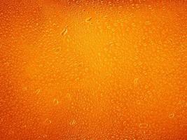 Water drops on orange background texture. backdrop glass covered with drops of water photo
