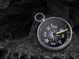 Compass nestled on black coal background. Travel destination and navigation concept photo