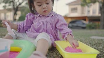 Babymädchen spielen mit kinetischem Sand im Park. video