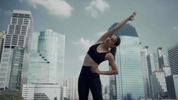 Sport woman wearing wireless headphones and stretching muscles before running in city, warmup exercise. video