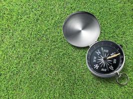 Compass on Green field of grass background. Travel destination and navigation concept photo