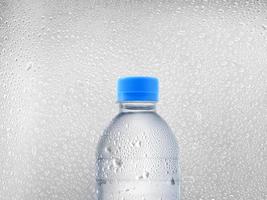 botella de agua sobre fondo de gotas de agua foto