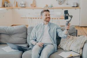 Young man in video call with friend while sitting on couch photo