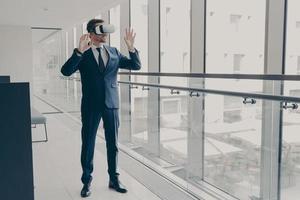 Successfu business professional in elegant suit standing in office and using VR technologies at work photo