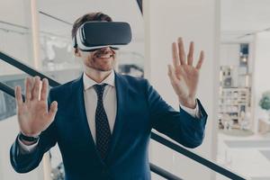 Young excited man office worker using virtual reality simulator at work, moving hands in air photo