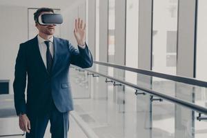 Excited office worker dressed in formal clothes managing business project through virtual reality photo