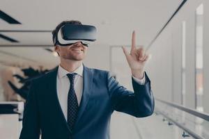 Cheerful businessman dressed formally using vr headset at work photo
