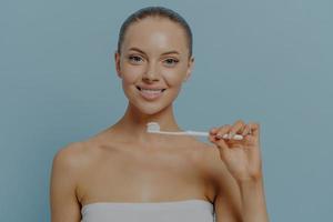 Dental. Young beautiful healthy woman holding toothbrush, brushing teeth with fluoride toothpaste photo