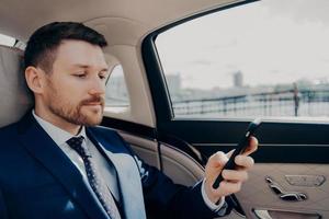 Investor checking his phone while riding in limousine photo