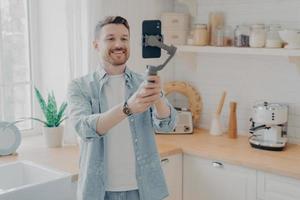 Young man blogger recording video blog with mobile phone at home photo