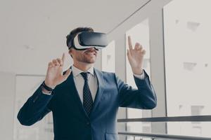 Excited office worker in vr headset or virtual reality goggles gesturing with hands photo