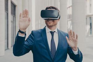 Businessman in suit trying out and experiencing virtual reality using mobile VR headset outdoors photo