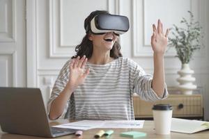 Excited amazed woman wearing VR glasses enjoying amazing virtual reality experience at work photo