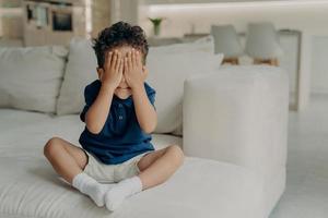 Small afro american boy playing hide and seek at home photo